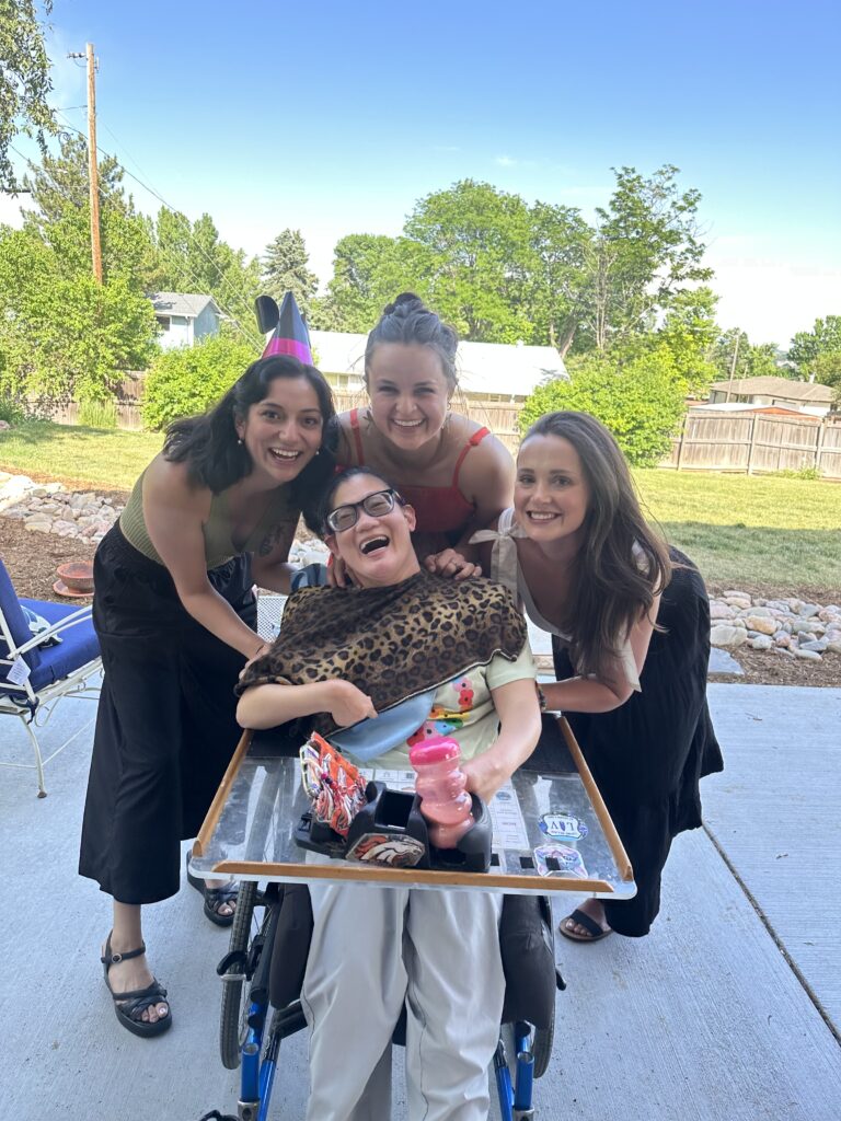 Mikelle is in her wheelchair smiling with three of her favorite girlfriends surrounding her with love.