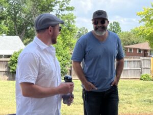 Two young men drinking beer in the backyard in summer.