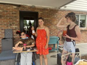 Woman in wheelchair speaking with two of her friends on a patio.