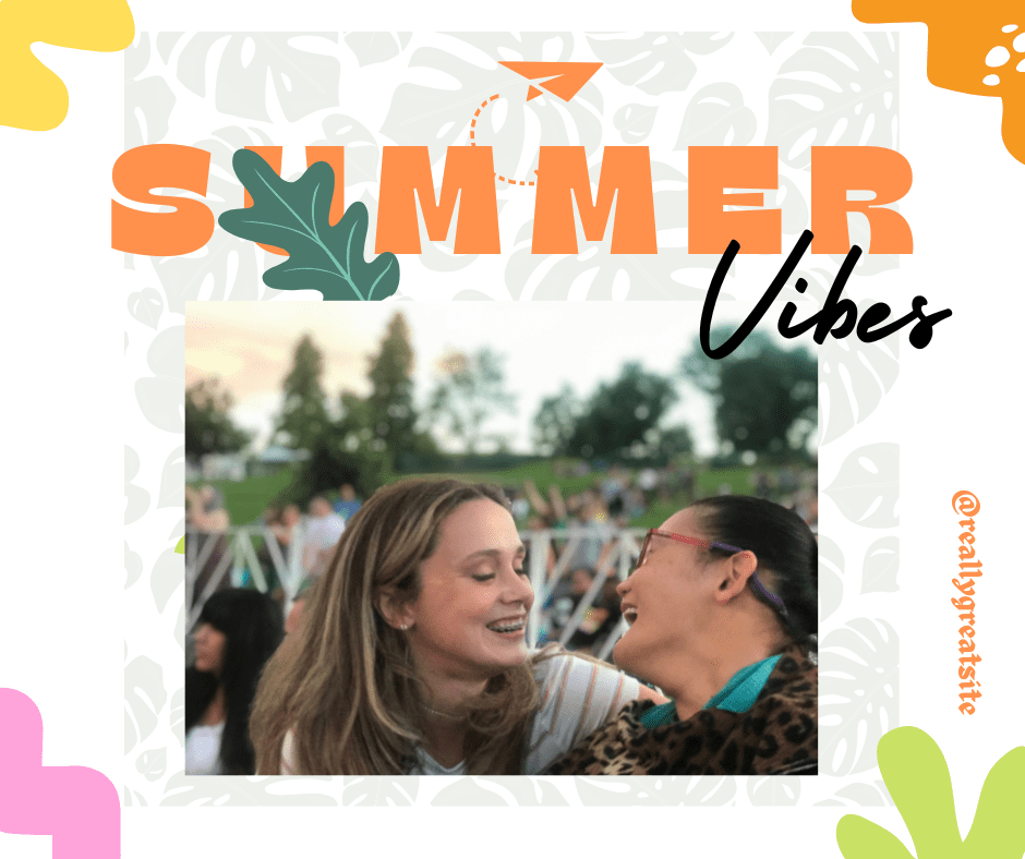 woman with dark hair in a bun with glasses looking at friend with long hair with affection at an outdoor concert/